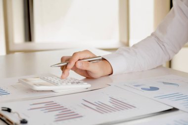 Bir iş adamı masada oturuyor ve gayrimenkul yatırımlarının finansal grafiklerini hesaplıyor..