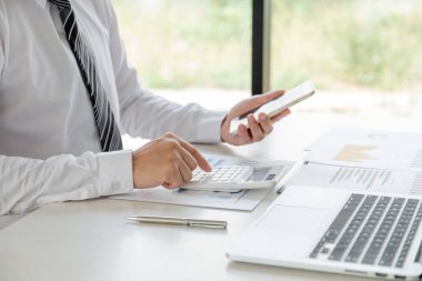 Bir iş adamı masada oturuyor ve gayrimenkul yatırımlarının finansal grafiklerini hesaplıyor..