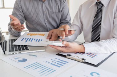 Sonuçları gösteren çizelge ve grafikleri tartışan iki iş lideri büyük başarı için yeni bir strateji başlatmayı planlıyor..