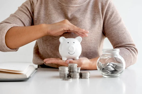 Women are putting coins in a piggy bank, glass bottle, saving money with coins, stepping into a growing business to succeed and save for retirement ideas.
