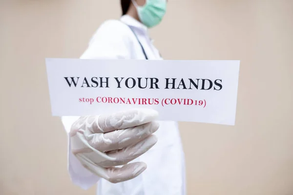 A female doctor who has a paper in his hand. WASH YOUR HANDS is at home to prevent infection the spread of the virus Covid-19, medical concepts and health care.