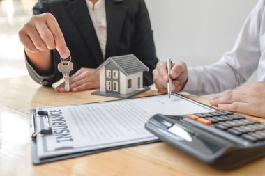 Emlak komisyoncusu imzayı attıktan sonra evin anahtarını ev kiralama ve ev sigortası konseptini satın alma anlaşmasına göre yeni sahibine teslim etti..