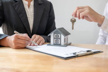 Emlak komisyoncusu imzayı attıktan sonra evin anahtarını ev kiralama ve ev sigortası konseptini satın alma anlaşmasına göre yeni sahibine teslim etti..