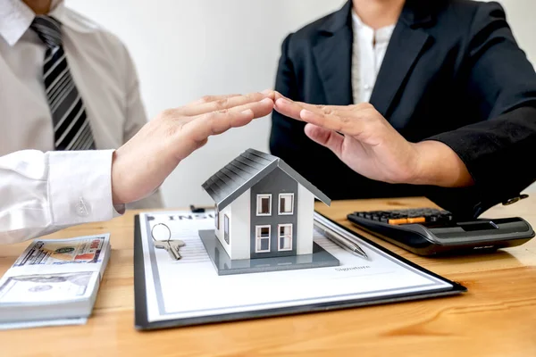 The house is covered by a  hand protecting to the client the buyer of the house in the real estate concept.