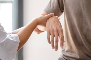 Kadın fizyoterapistler, dirsek yaralanması olan erkek hastalara rehabilitasyon merkezlerindeki hastaları muayene etmede yardımcı oluyorlar. Fizyoterapi kavramları.
