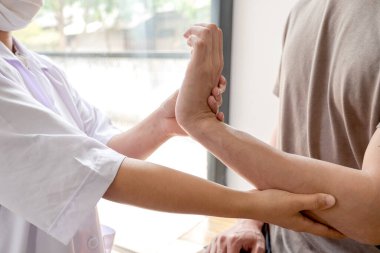 Kadın fizyoterapistler rehabilitasyon merkezinde bilek yaralanması olan erkek hastalara yardım ediyor. Fizik tedavi kavramları.