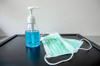 Tıbbi maske ve alkol el dezenfektanının fotoğrafı, mikropları önlemek için kirli çamaşır..