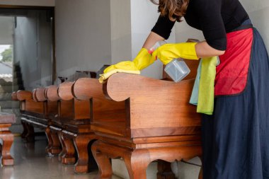 Lastik eldivenli mutlu ev kadınları masaları ve sandalyeleri temizlerken tozu spreyle silerler..
