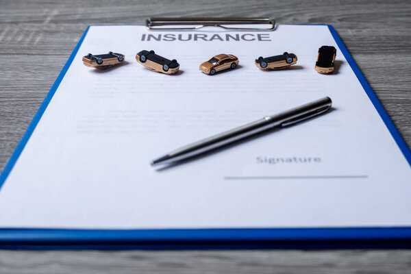 Car and pen on insurance documents. Car insurance concept.