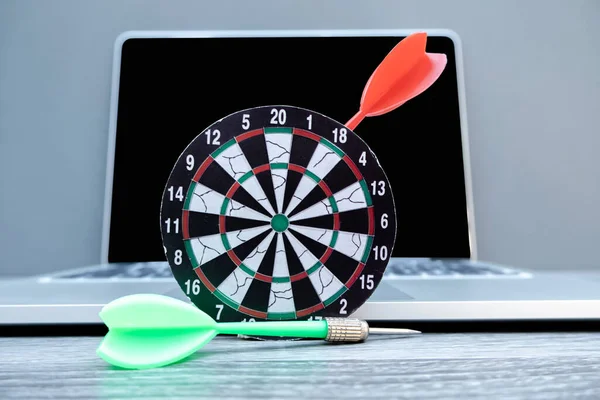 The small dartboard and the arrow located with laptop represent successful business goals concept.