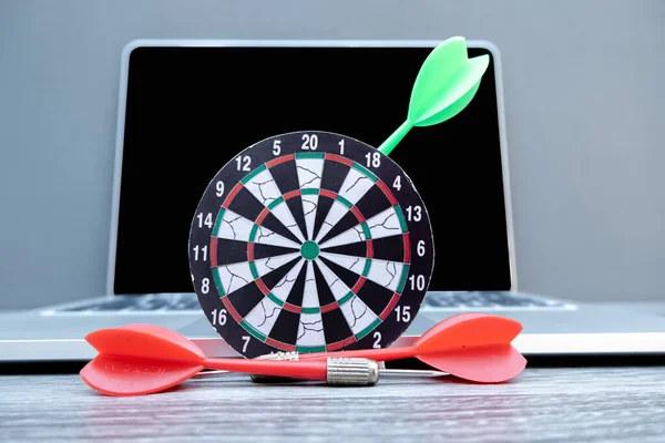 The small dartboard and the arrow located with laptop represent successful business goals concept.