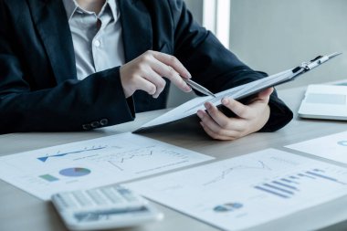 İşadamı bir masada oturuyor ve sonuçları gösteren finansal grafiği hesaplıyor..