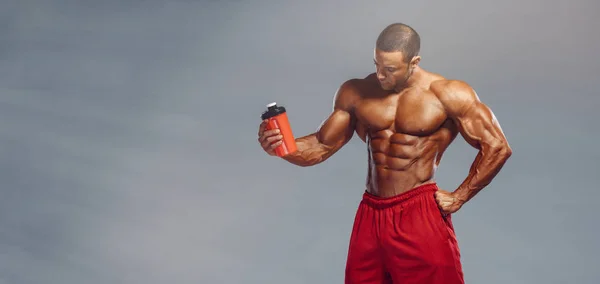 Питательное дополнение. Мускулистые мужчины пьют протеин, энергетический напиток после тренировки — стоковое фото