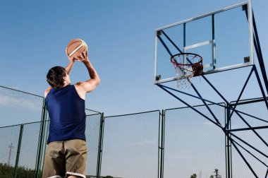 Genç Spor Adamları Güneşli bir günde dışarıda basketbol oynuyor.