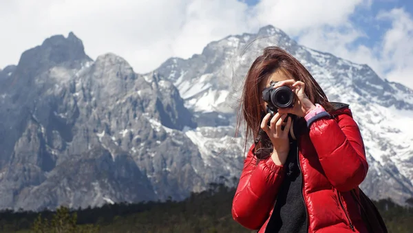 Genç kız fotoğrafçı holding nikon Dslr, o kuvvet Öte yandan, kar dağ Jade Dragon arka planda Lijiang, kışın dağ geniş Yunnan Çin