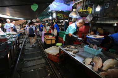 Bangkok / Tayland -29 Aralık 2019: Mae Klong demiryolu pazarı. Bangkok 'ta ünlü bir ziyaret yeri. Demiryolu inşaatı ve tren geliyor. Pazarcı trenin yolunu açacak..