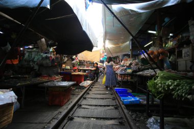 Bangkok / Tayland -29 Aralık 2019: Mae Klong demiryolu pazarı. Bangkok 'ta ünlü bir ziyaret yeri. Demiryolu inşaatı ve tren geliyor. Pazarcı trenin yolunu açacak..
