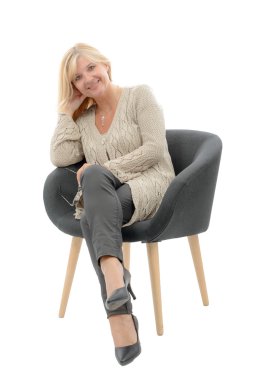 Portrait of blond mature woman relaxing in armchair clipart