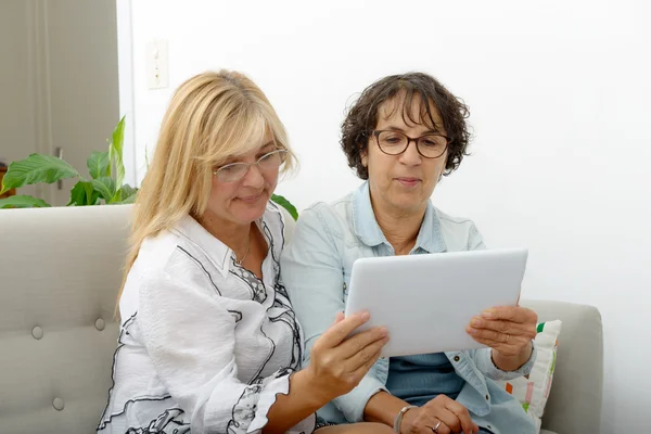 Two attractive mature women websurfing with tablet — Stock Photo, Image