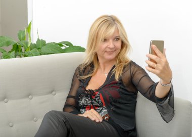 Smartphone kullanarak gülümseyen Olgun kadın