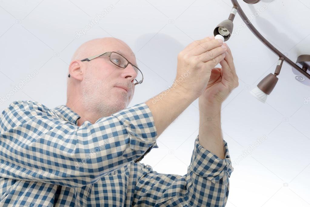 Man replacing the light bulb at home