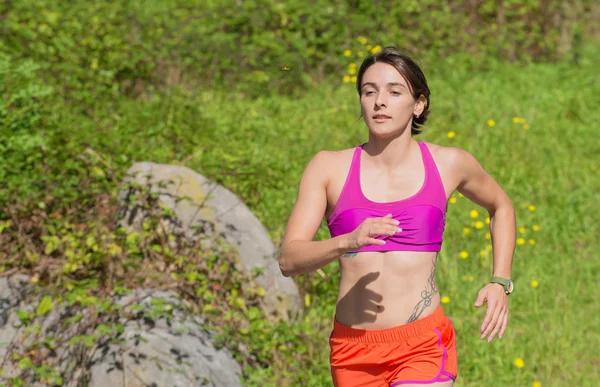 Beautiful athletic woman running in countryside — Stock Photo, Image