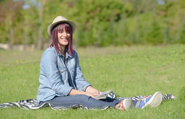 Mooie jonge vrouw zitten in het gras — Stockfoto