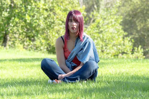 Beautiful young woman sitting in the grass — Stock Photo, Image