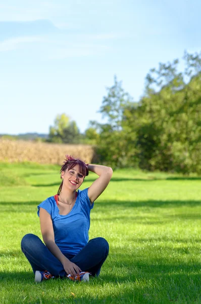 Beautiful young woman sitting in the grass — Stock Photo, Image