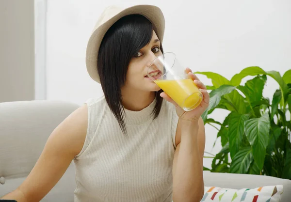 若い学生のソファでオレンジ ジュースを飲む — ストック写真