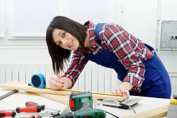 Graziosa ragazza costruttore misurare un asse di legno — Foto Stock