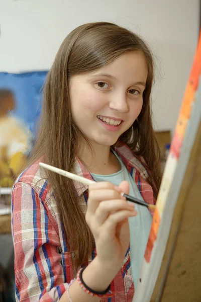 Улыбающийся молодой подросток рисует холст — стоковое фото