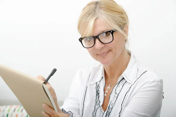 Hermosa mujer madura escribiendo en un cuaderno — Foto de Stock