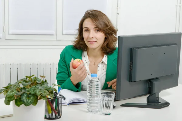 Uśmiechnięta młoda kobieta w biurze gospodarstwa apple — Zdjęcie stockowe