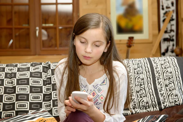 Giovane adolescente sul divano invia un messaggio di testo — Foto Stock