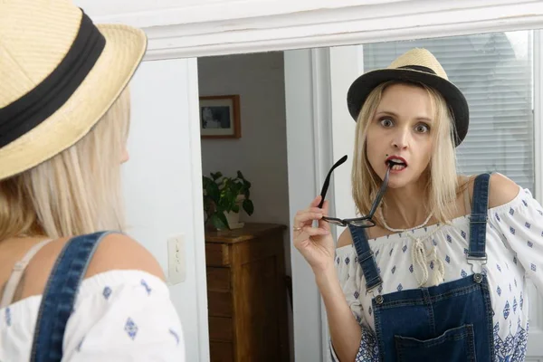 Schöne blonde Frau posiert mit Sommermütze im Spiegel — Stockfoto