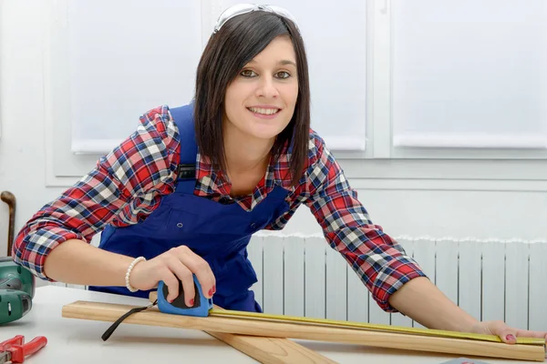 Bonita niña constructora midiendo una tabla de madera —  Fotos de Stock