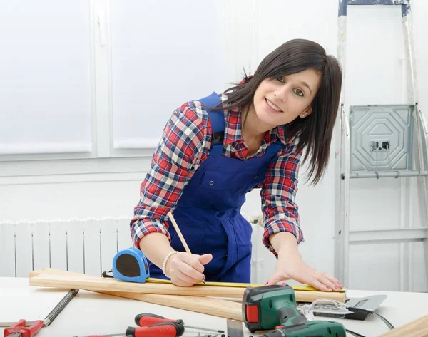 Graziosa ragazza costruttore misurare un asse di legno — Foto Stock