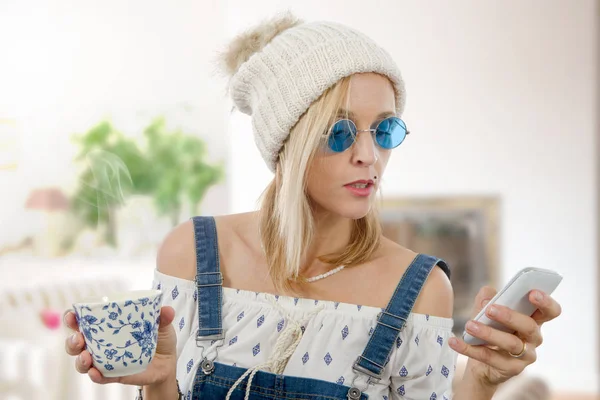 Bella donna bionda con una tazza di tè e telefono — Foto Stock