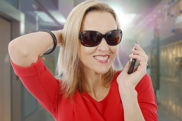Blonde Geschäftsfrau mittleren Alters mit Telefon und Sonnenbrille — Stockfoto
