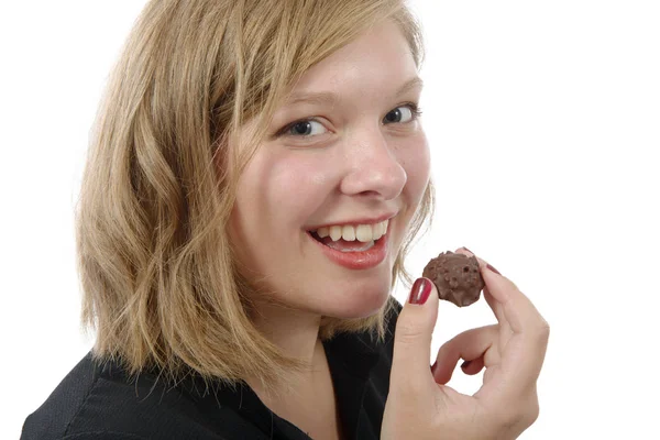 Uśmiechnięta młoda kobieta jedzenie cukierków czekoladowych — Zdjęcie stockowe