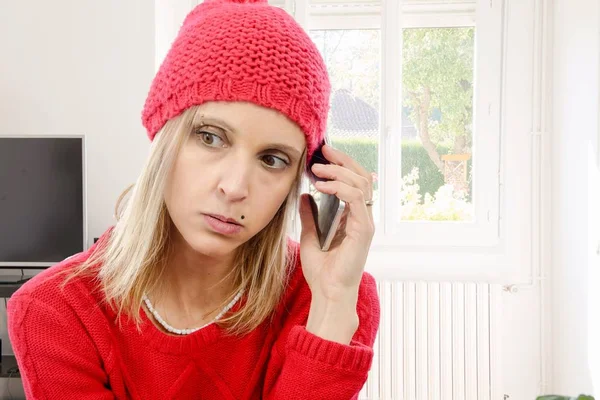 Schöne junge blonde Frau mit roter Mütze, Telefon — Stockfoto