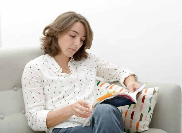 Piękna młoda kobieta z książką w kanapie — Zdjęcie stockowe
