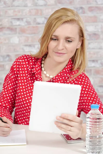Mooie jonge blonde vrouw met rode shirt en tablet — Stockfoto