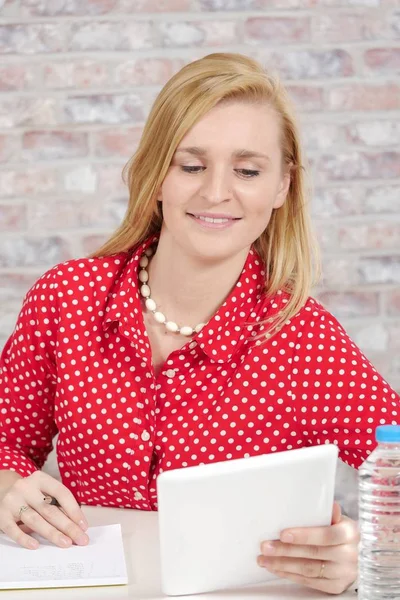 Mooie jonge blonde vrouw met rode shirt en tablet — Stockfoto