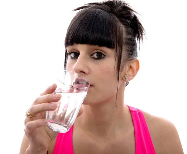 Ung flicka dricker ett glas vatten, på vitt — Stockfoto