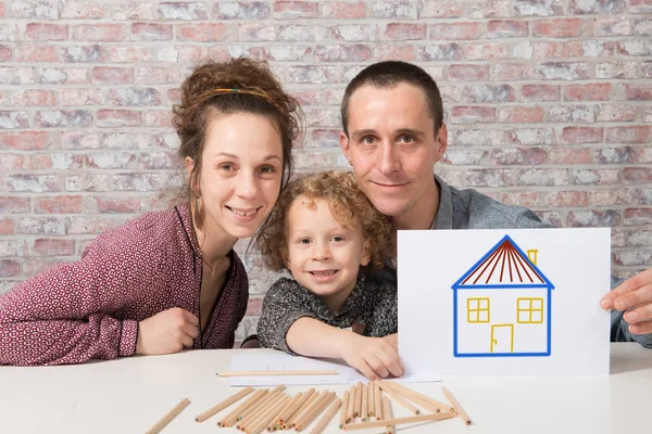 Lycklig familj, barn håller papper med rita hus — Stockfoto