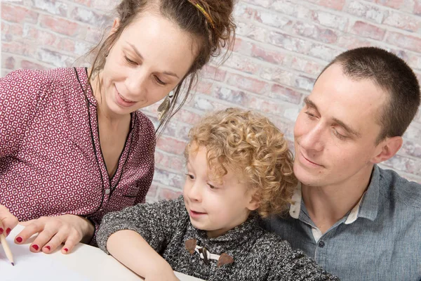 Little blond  boy drawing with his parents — Stock Photo, Image