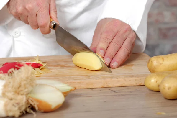 Détail des mains du chef tranchant des pommes de terre — Photo