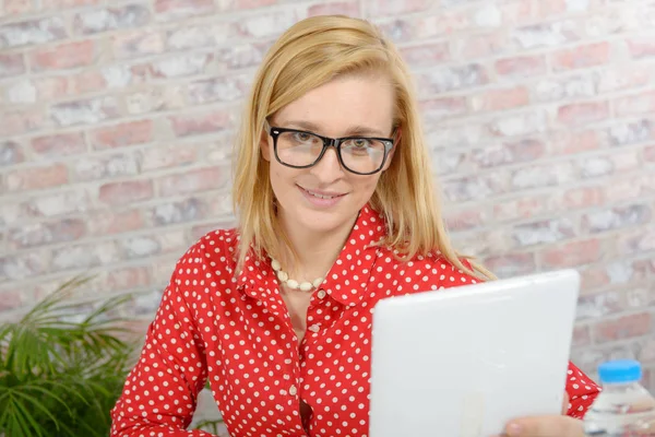 Mooie jonge blonde vrouw met rode shirt met behulp van Tablet PC — Stockfoto